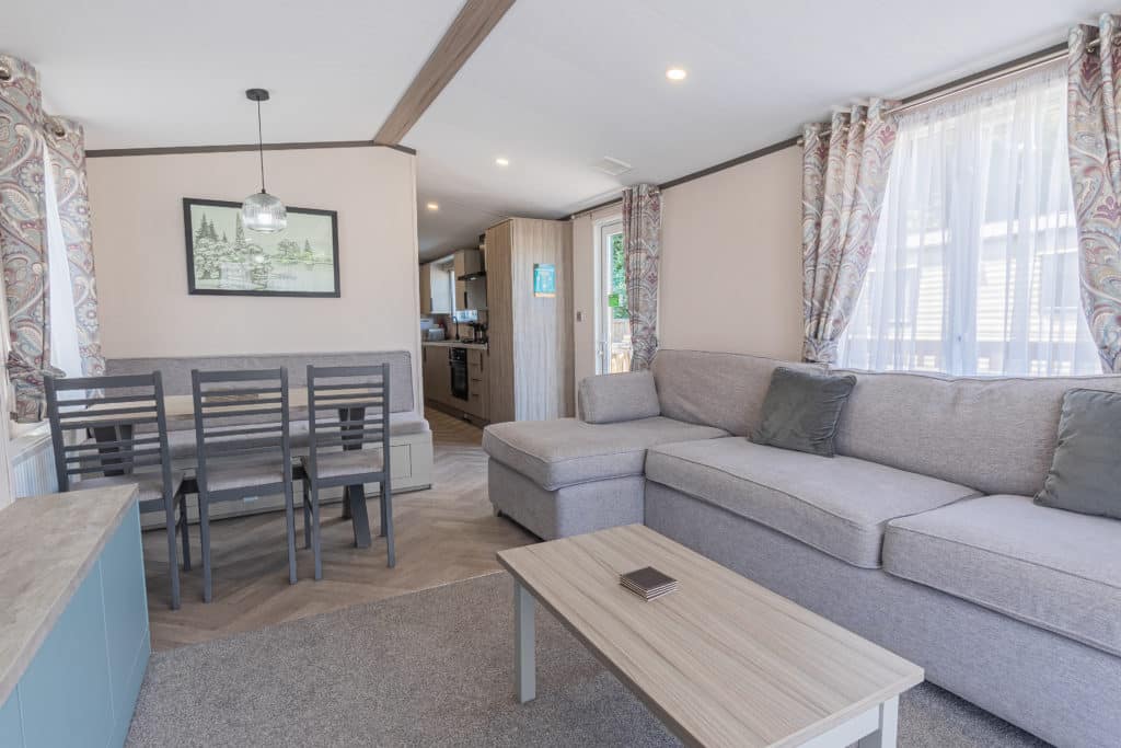 Oakcliff's Lapwing Mini Lodge open-plan living area. Including a large family-style sofa, dining table and kitchen.