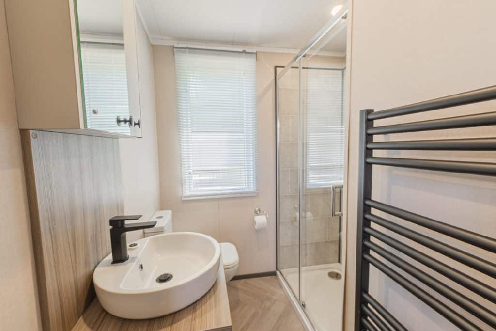 Oakcliff's Lapwing Mini Lodge bathroom with shower, sink, toilet and towel rail