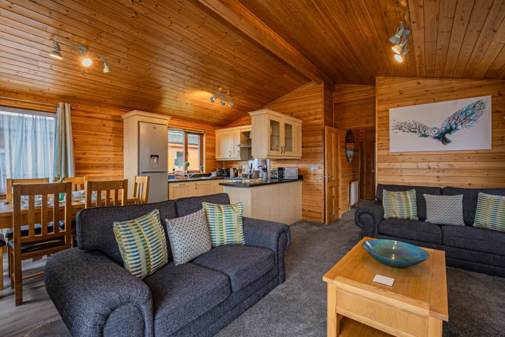 Oakcliff's Pine Lodge open-plan living room with the kitchen in the background.