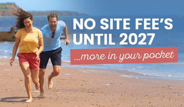 A couple running on the beach with "no site fee's until 2027" written