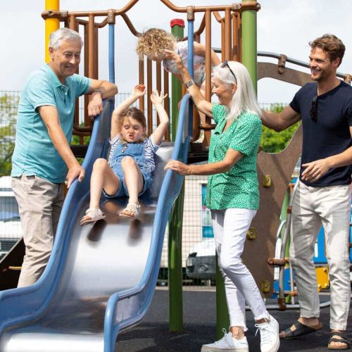A family watching their child go down a slide
