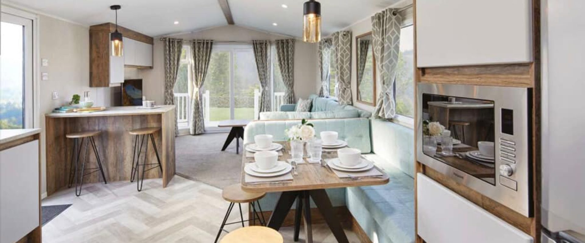 Oakcliff's Lapwing Plus Mini Lodge modern open-plan living area. Showing a breakfast bar, dining table and lounge.