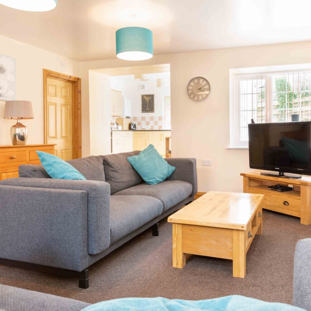 Oakcliff's Mews Cottage living room. With a stylish sofa, coffee table and TV.