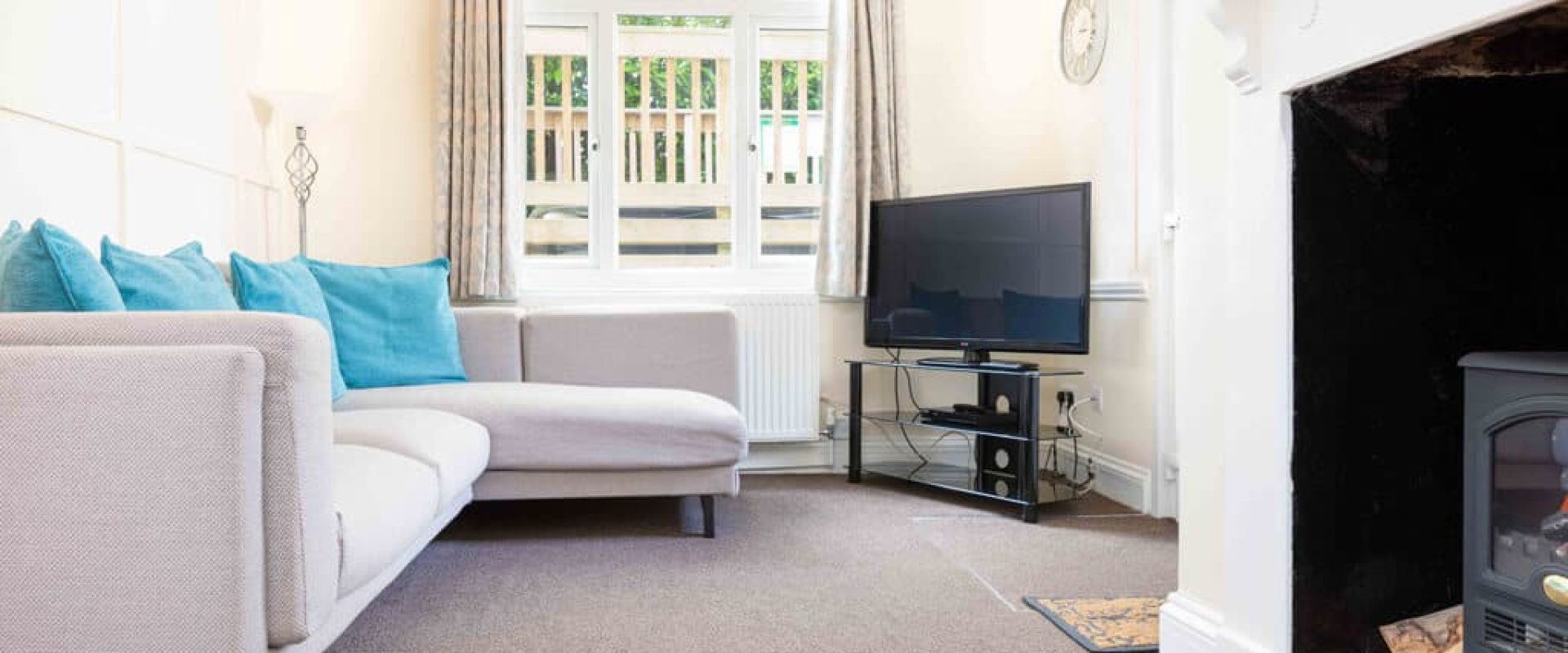 Oakcliff's Oak Cottage living room. With large windows, an L-shape sofa and TV.