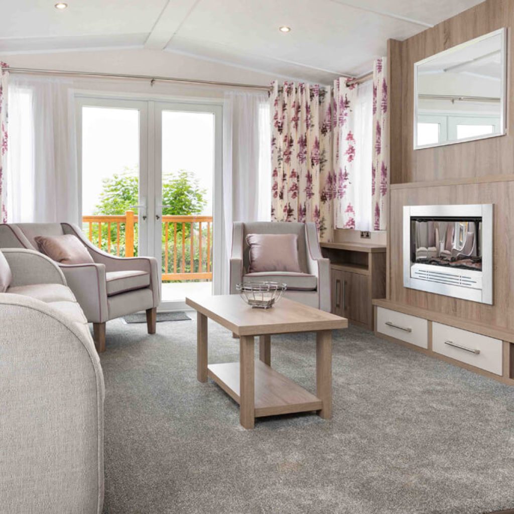 Oakcliff's Osprey Premier Mini Lodge living room. Including multiple sofas, a coffee table and built-in fire.