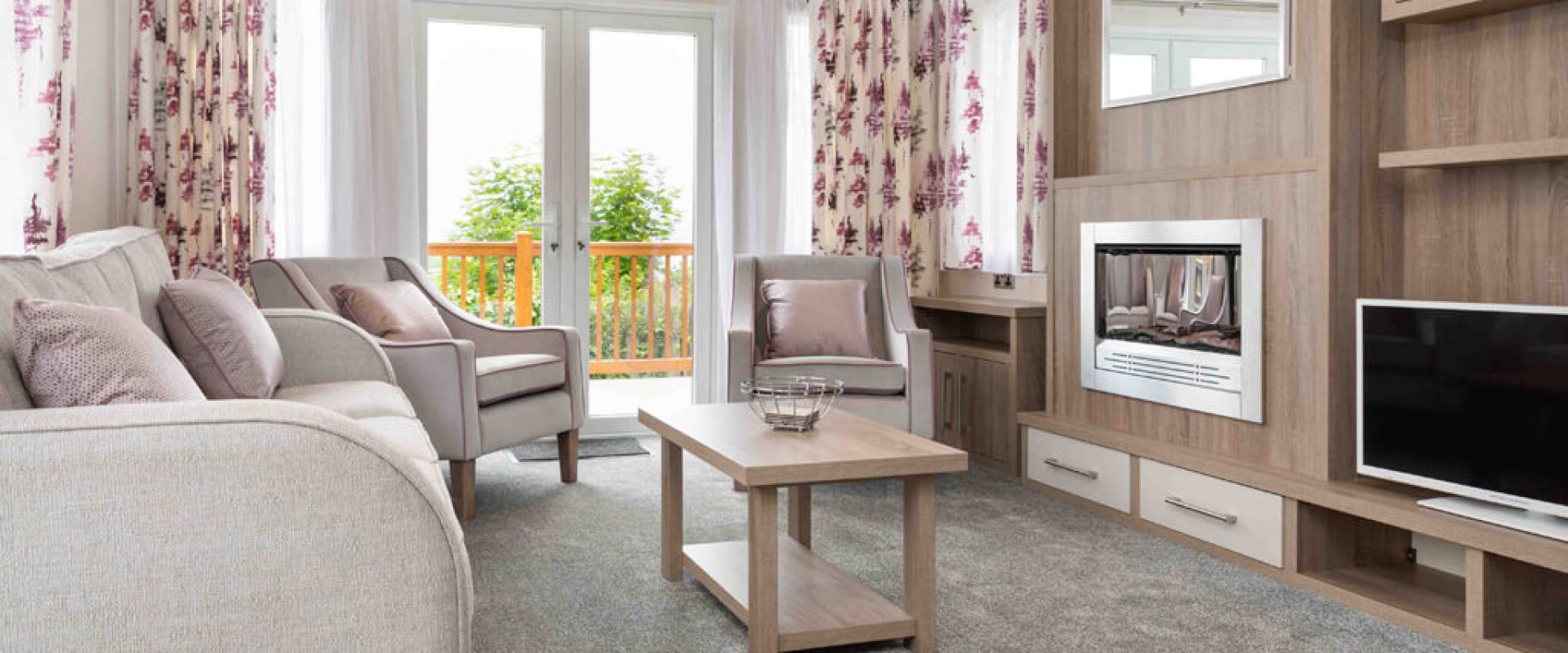 Oakcliff's Osprey Premier Mini Lodge living room. Including multiple sofas, a coffee table and built-in fire.