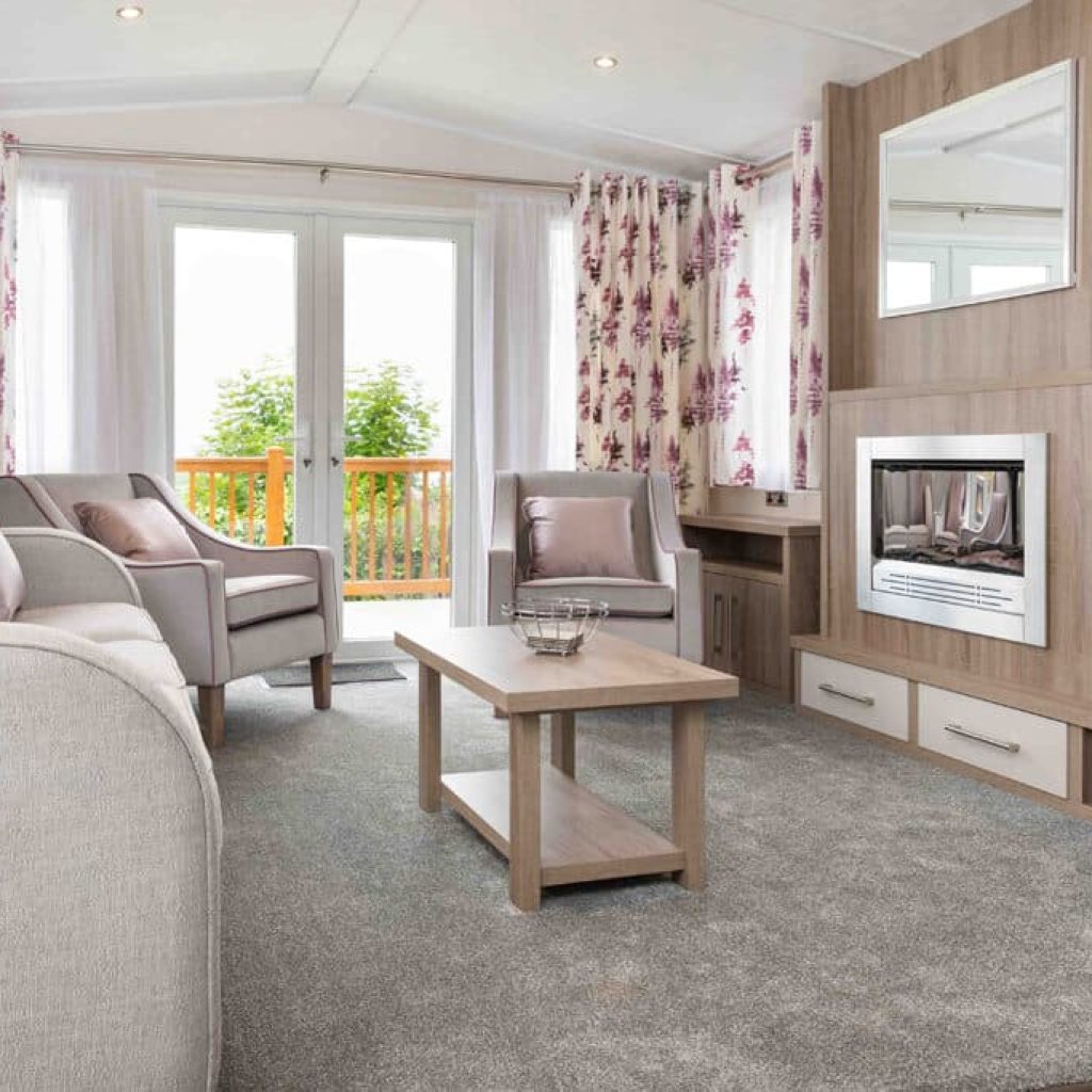 Oakcliff's Osprey Premier Mini Lodge living room. Including multiple sofas, a coffee table and built-in fire.