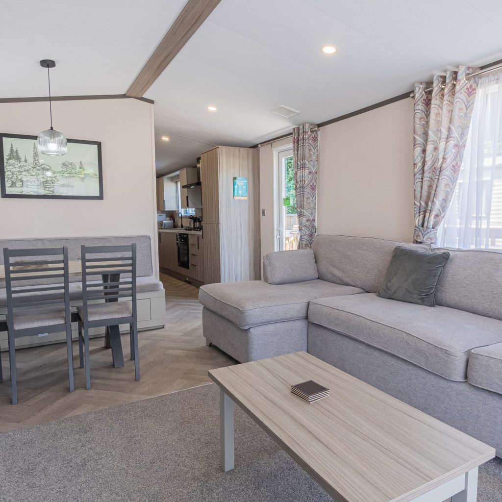 Oakcliff's Lapwing Mini Lodge open-plan living area. Including a large family-style sofa, dining table and kitchen.