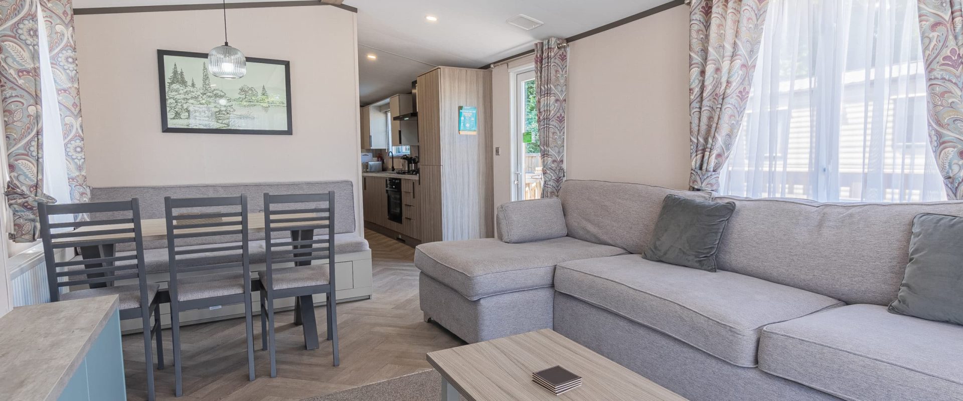 Oakcliff's Lapwing Mini Lodge open-plan living area. Including a large family-style sofa, dining table and kitchen.