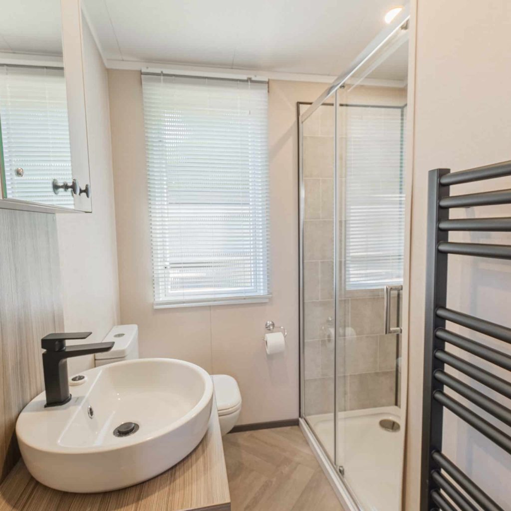 Oakcliff's Lapwing Mini Lodge bathroom with shower, sink, toilet and towel rail