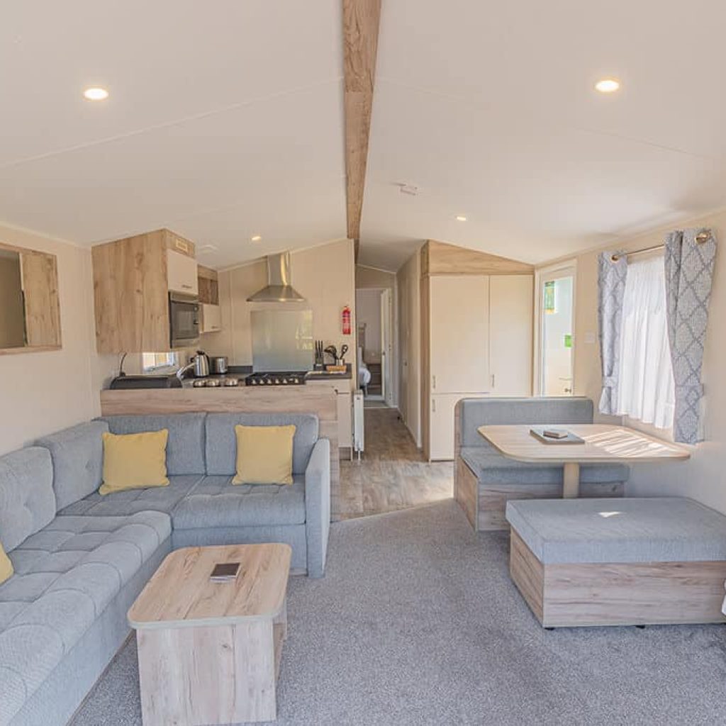 Oakcliff's Wren Plus Caravan open-plan living area. Including a family-style sofa, dining table and kitchen