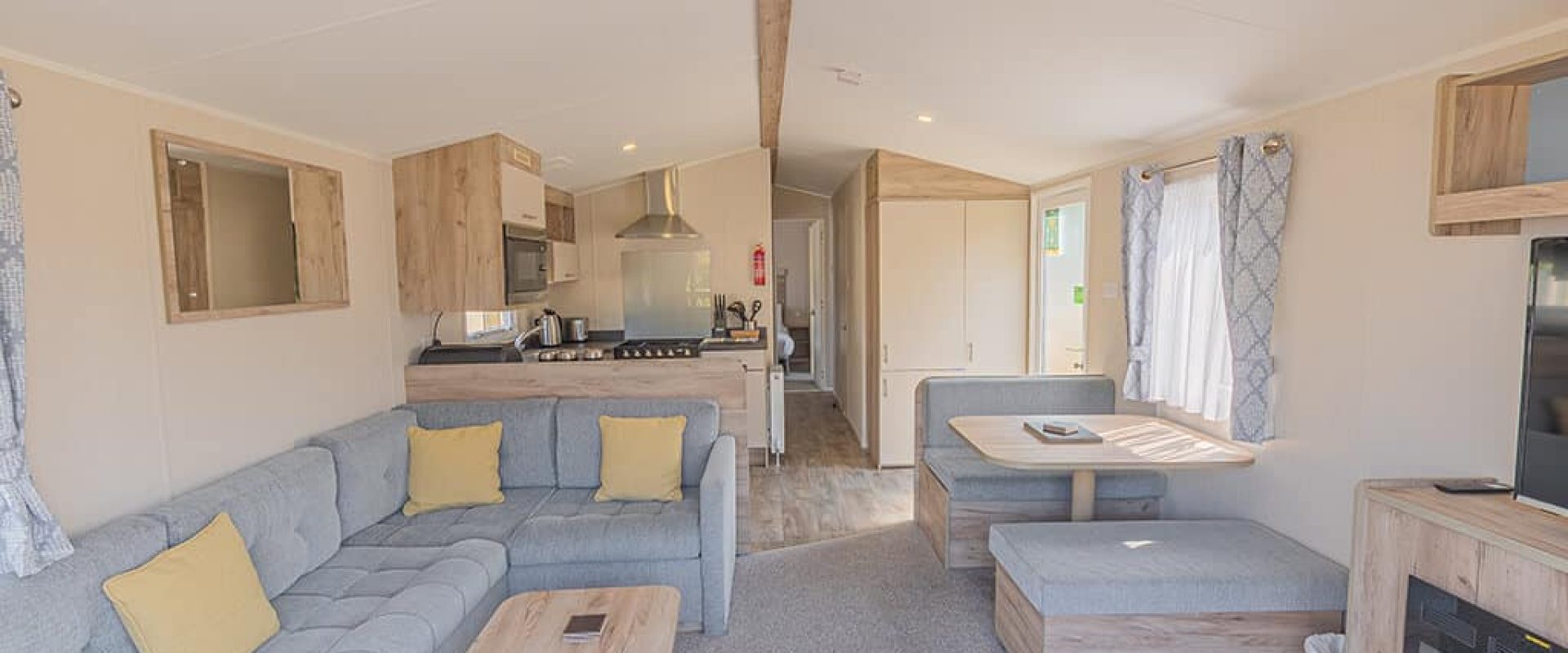 Oakcliff's Wren Plus Caravan open-plan living area. Including a family-style sofa, dining table and kitchen