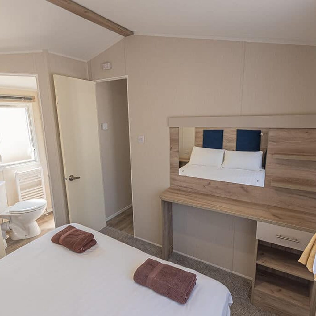 Oakcliff's Wren Plus Caravan double bedroom with a wall-mounted mirror