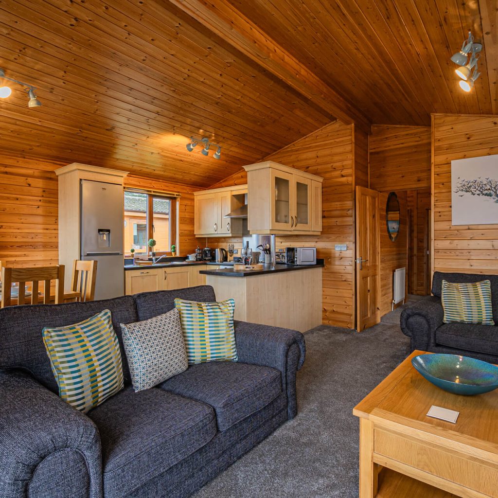 Oakcliff's Pine Lodge open-plan living room with the kitchen in the background.