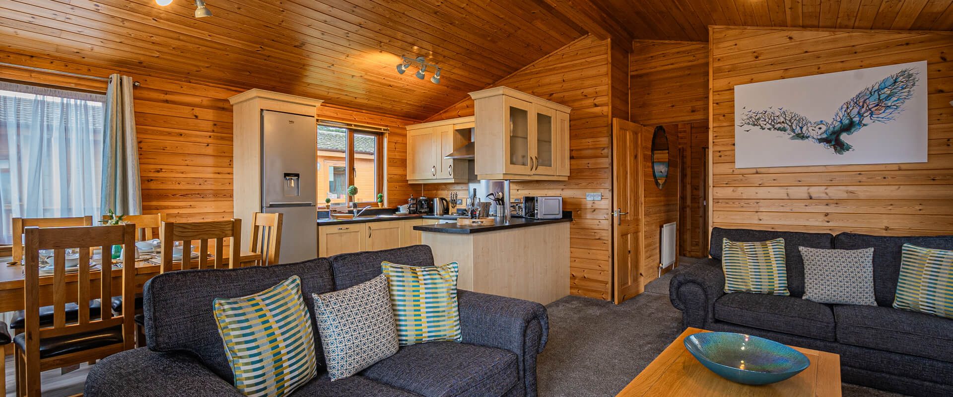 Oakcliff's Pine Lodge open-plan living room with the kitchen in the background.